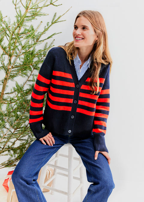 Model sitting in front of a Christmas tree wearing the Raffa - Navy/Poppy